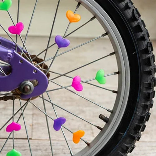 Close-up of a bicycle wheel with colorful heart-shaped objects attached to the spokes.