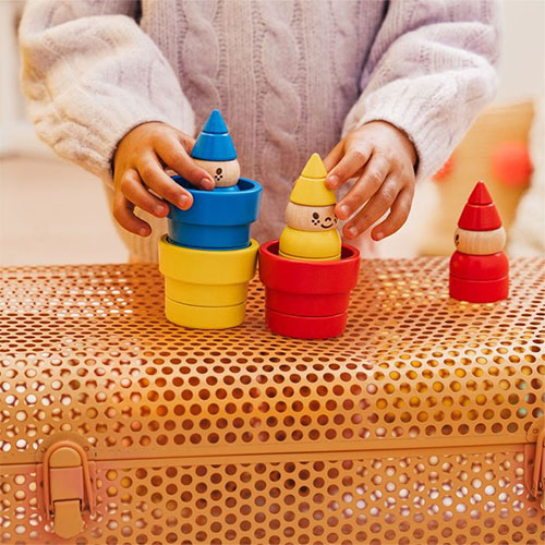 Child playing with colorful wooden stacking toys on a textured surface Gnomes Sweet Gnomes Smart Games Logic Game Whirligig Toys